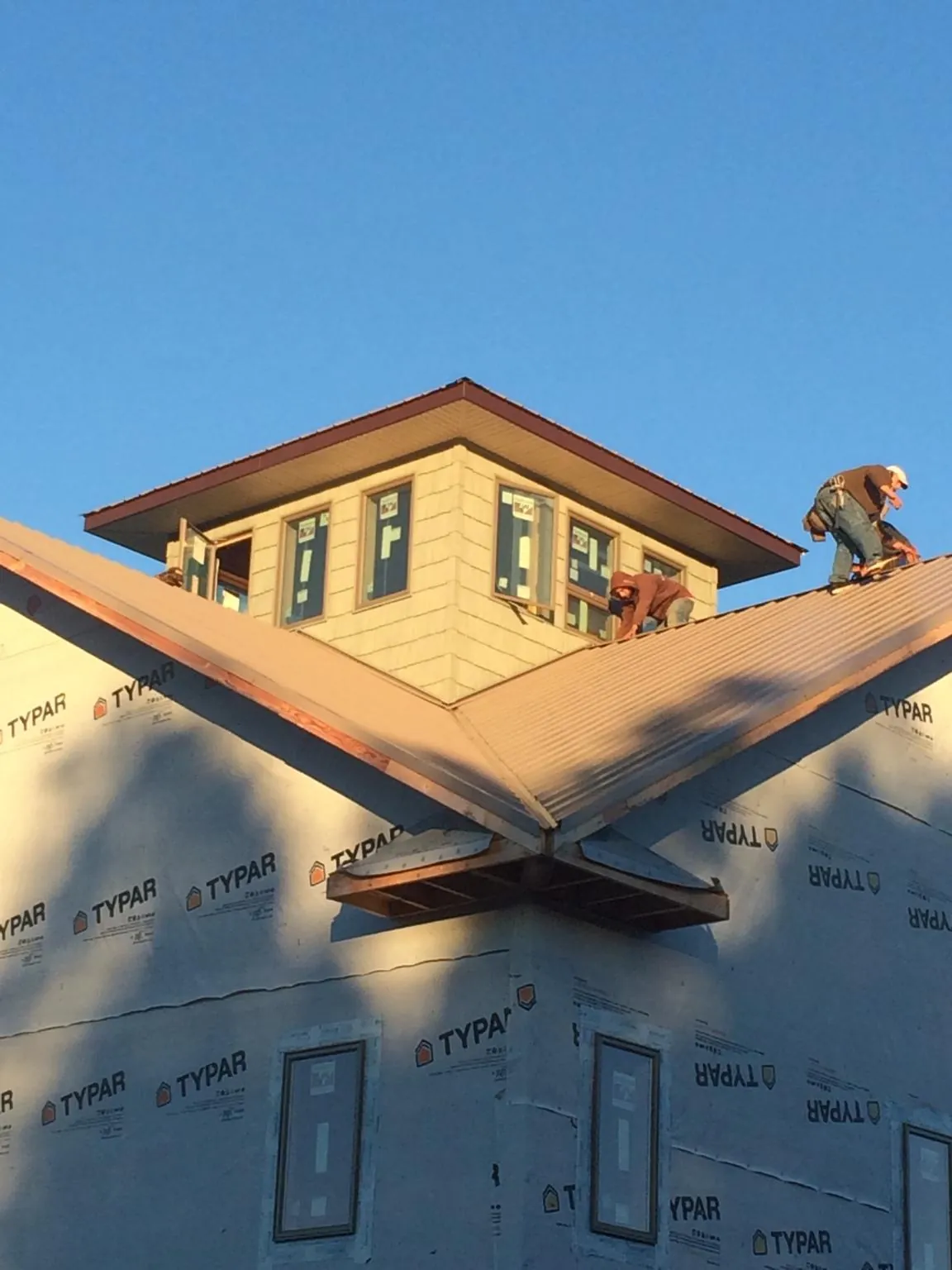 Roofers working around a rooftop cupola on a new metal roof at sunset — Roof Waterproofing in Manzanola by Roofing Brothers
